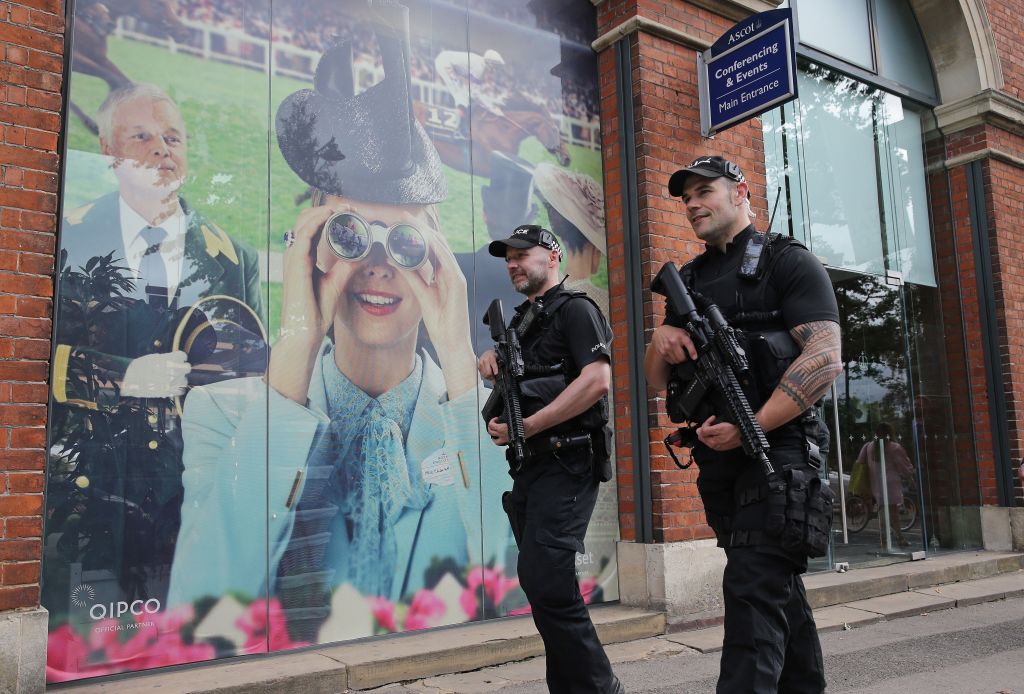 Armed British police officers carry their weapons as they patrol outside the entrance on day one of the Royal Ascot 