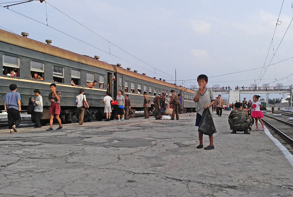 A little boy begs for food on the platform in Hamhung Railway Station