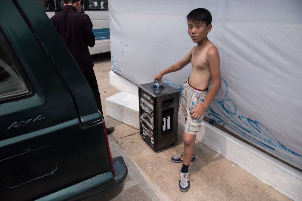 a boy standing with a karaoke machine at the West Sea Barrage beach outside the coastal city of Nampho, southwest of Pyongyang