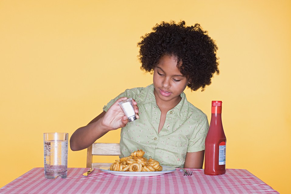 Girl putting salt on curly fries