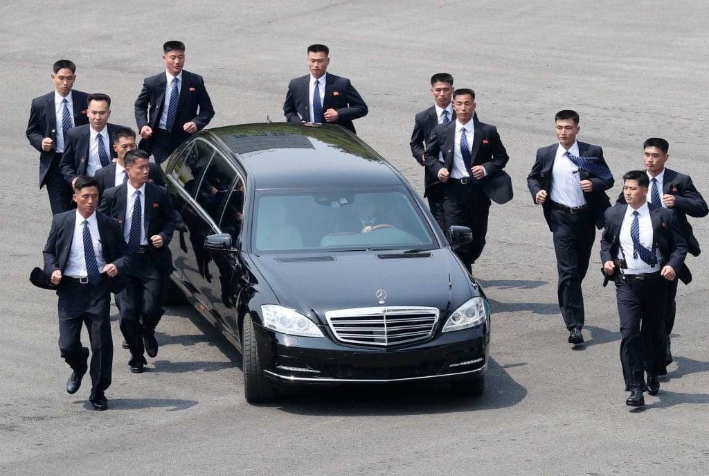 North Korean bodyguards jog next to a car carrying North Korea's leader Kim Jong Un