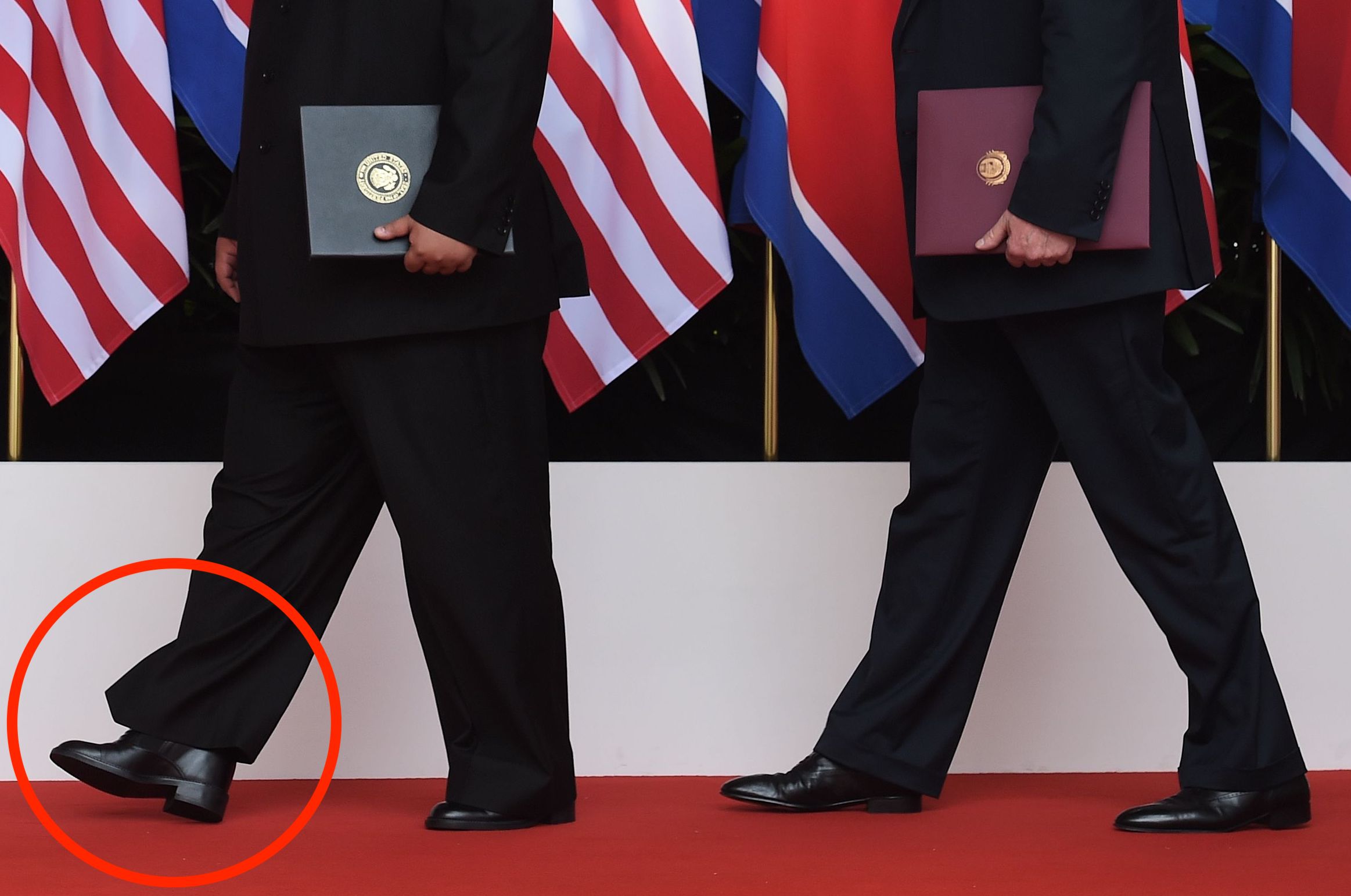 US President Donald Trump (R) poses with North Korea's leader Kim Jong Un focus on shoes