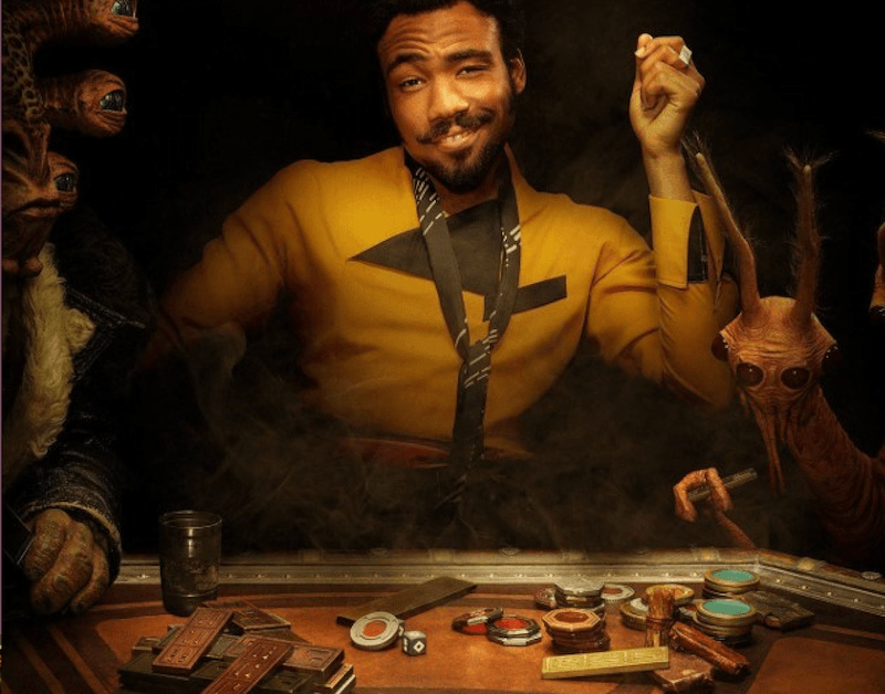 Lando sitting at a table with tokens and cards. 