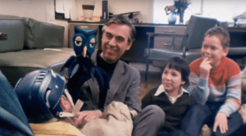 Mister Rogers showing a puppet to children. 