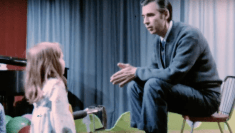 Mister Rogers speaking to a child on set. 