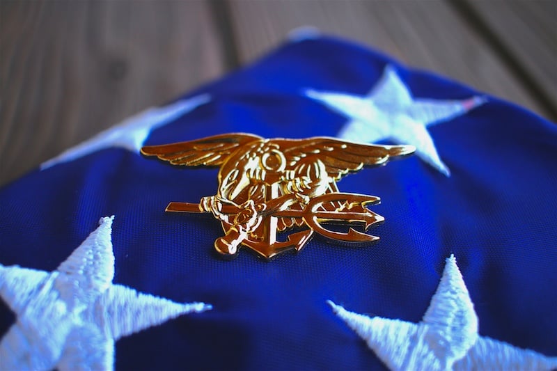 Navy SEAL trident rests atop a folded American flag