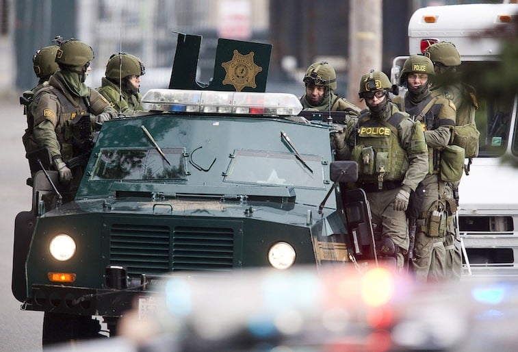 SWAT team members ride on a armored vehicle