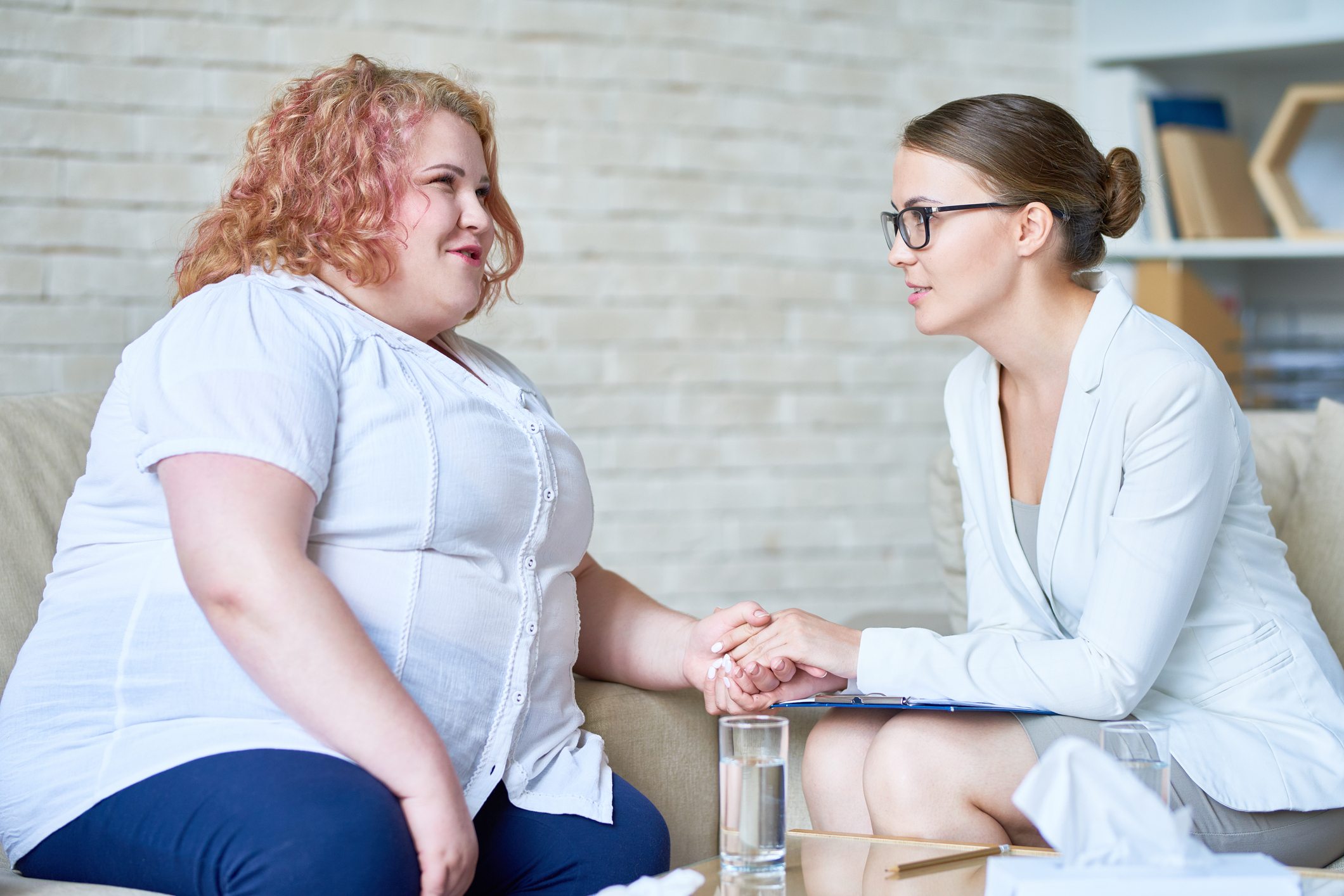An overweight woman speaks with a a therapist.