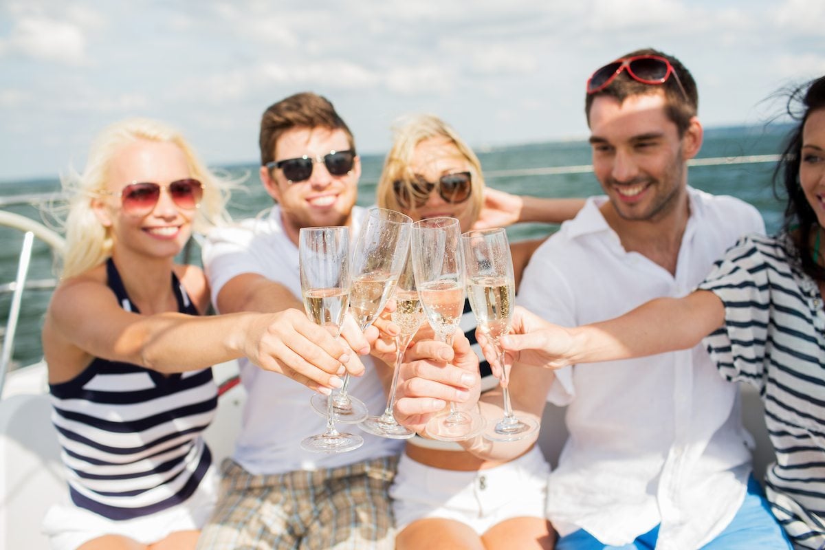 Friends toast glasses of champagne on a yacht
