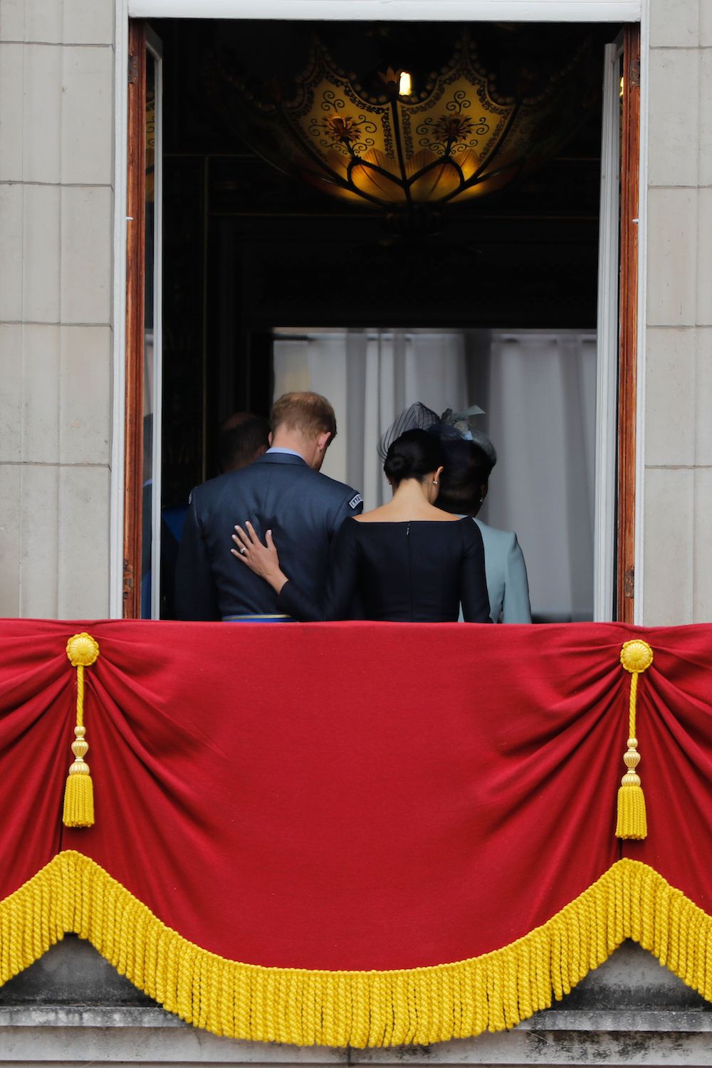 Meghan Markle puts her hand on Prince Harry's back as they leave the balcony of Buckingham Palace