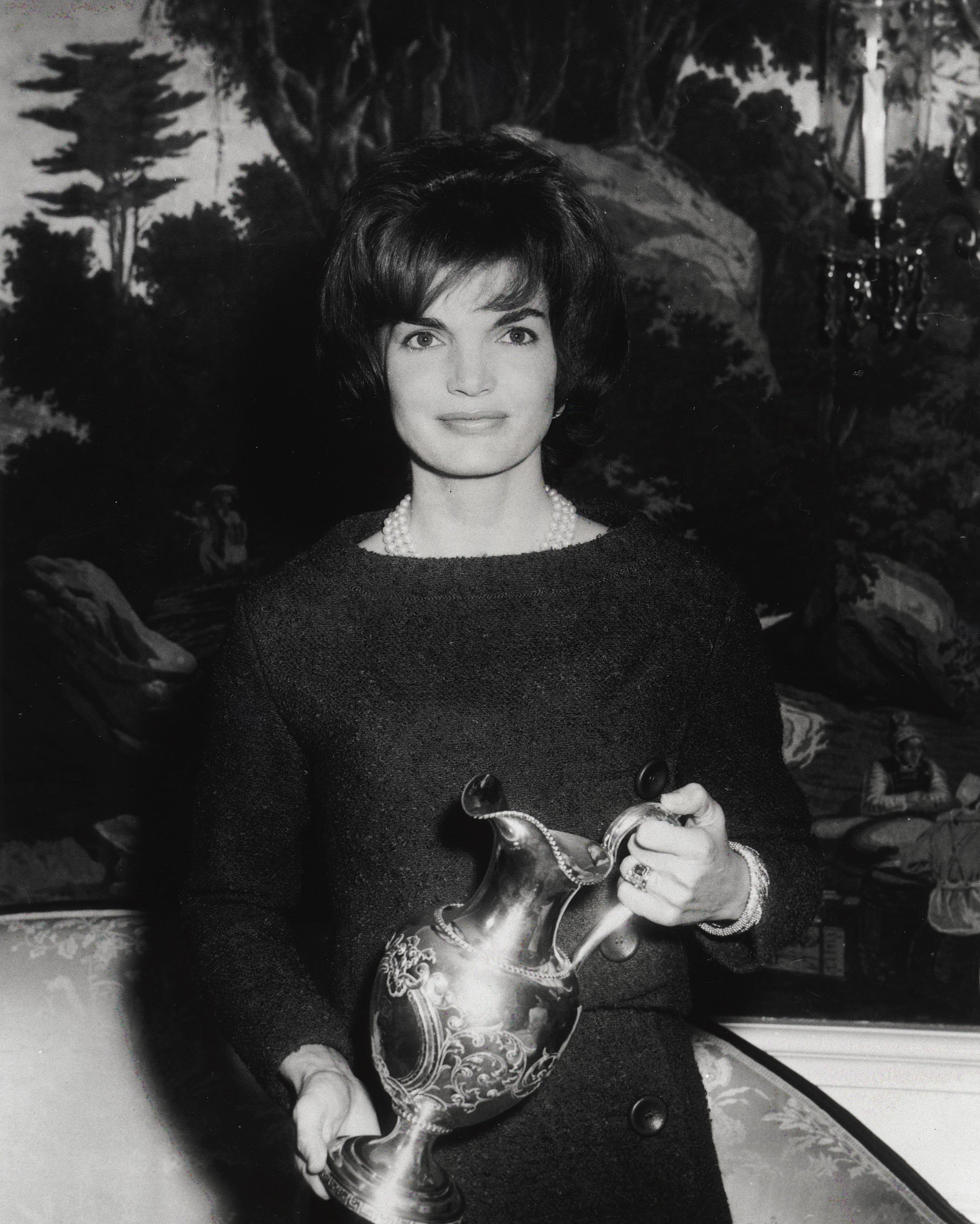 First Lady Jacqueline Kennedy poses for a photograph while holding a gift