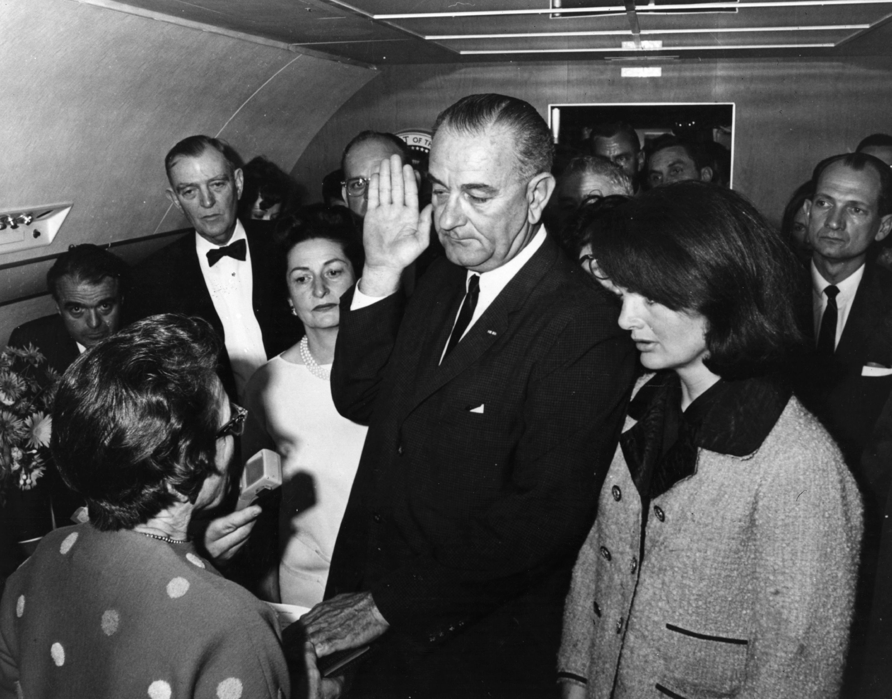 Lyndon Baines Johnson is sworn in as the 36th President of the United States of America on board the presdential aeroplane, after the assassination of President John F Kennedy. Mrs Johnson is behind him, left, and to his right is the grief stricken Jackie Kennedy