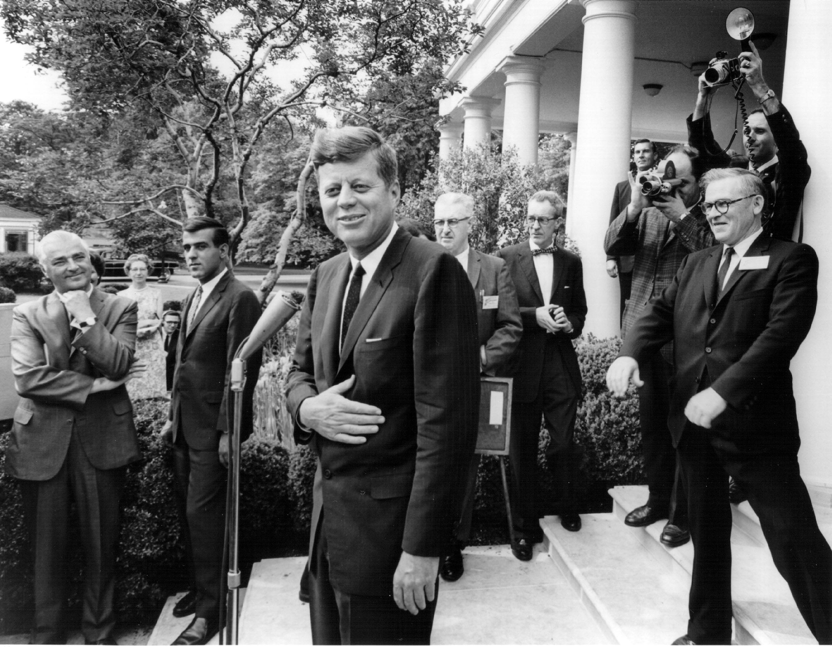 John F. Kennedy laughs with reporters after a White House press conference