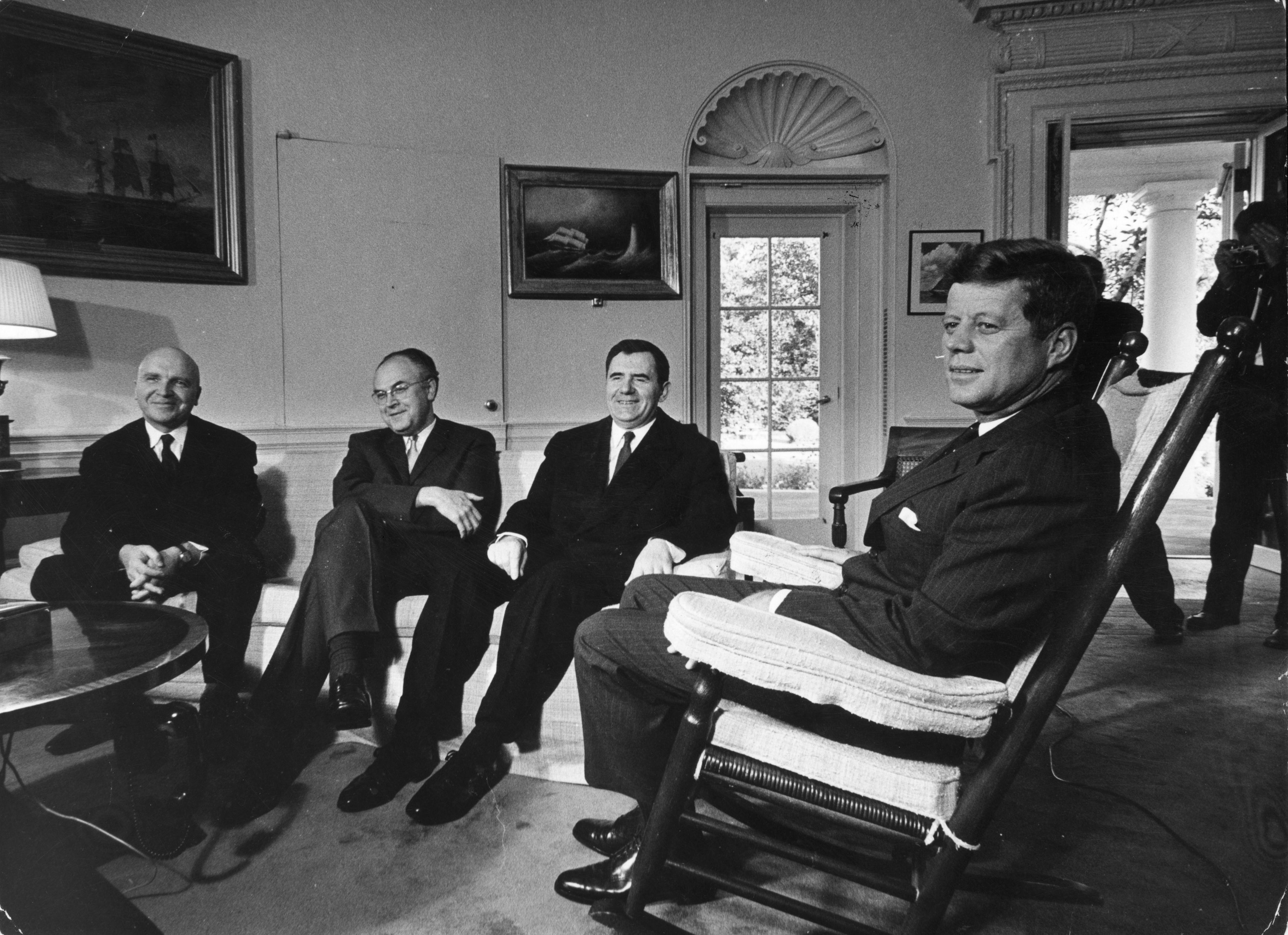 John F. Kennedy sits in a rocking chair in the Oval Office