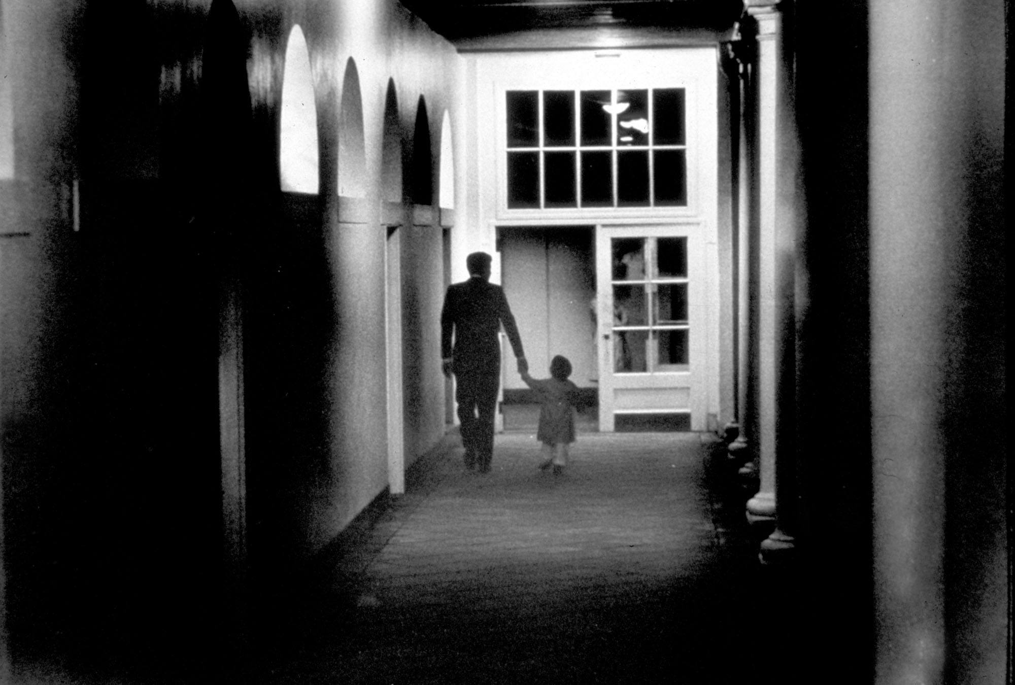 John F. Kennedy walks his son down the hall at the White House