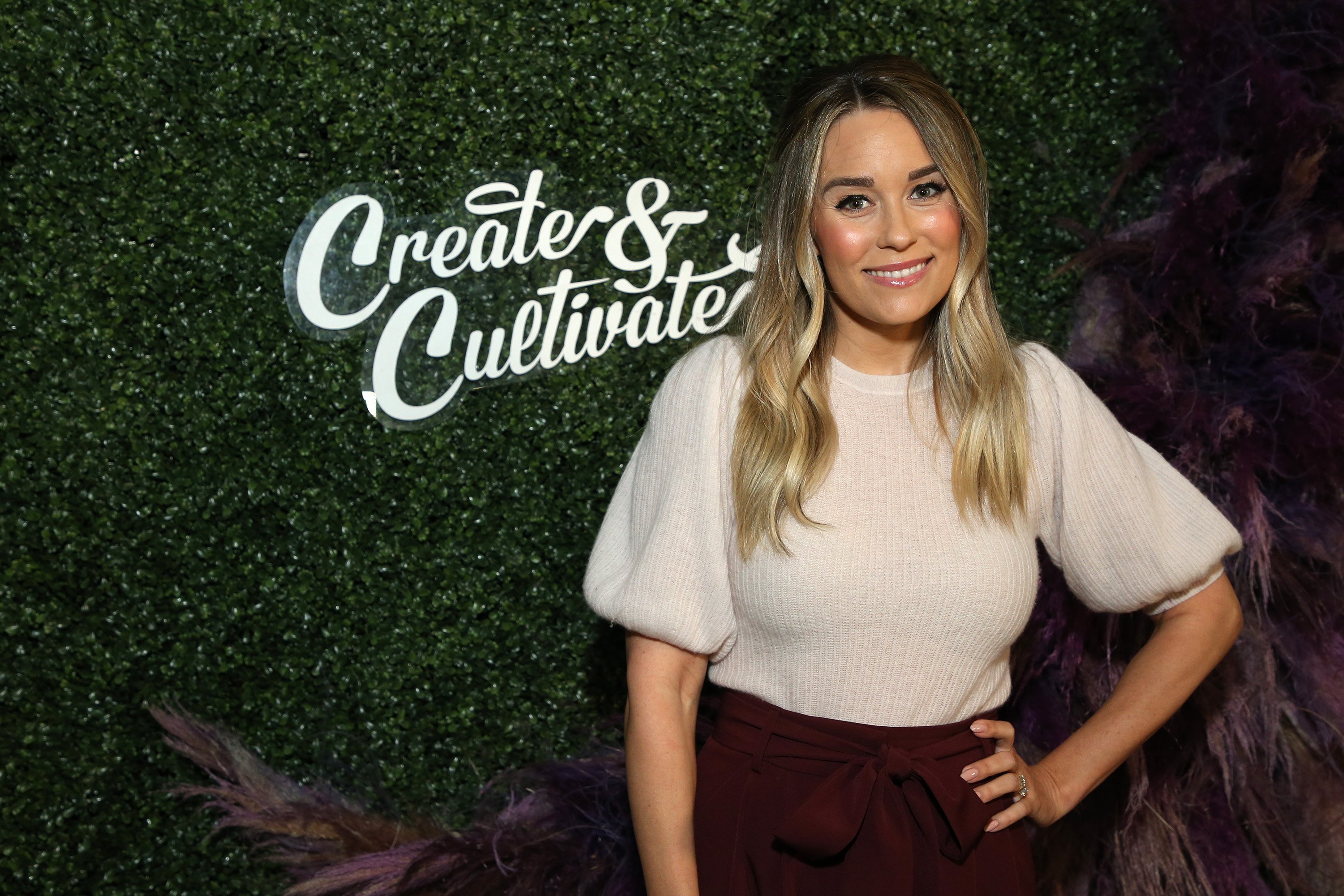 Lauren Conrad in front of a green photo wall