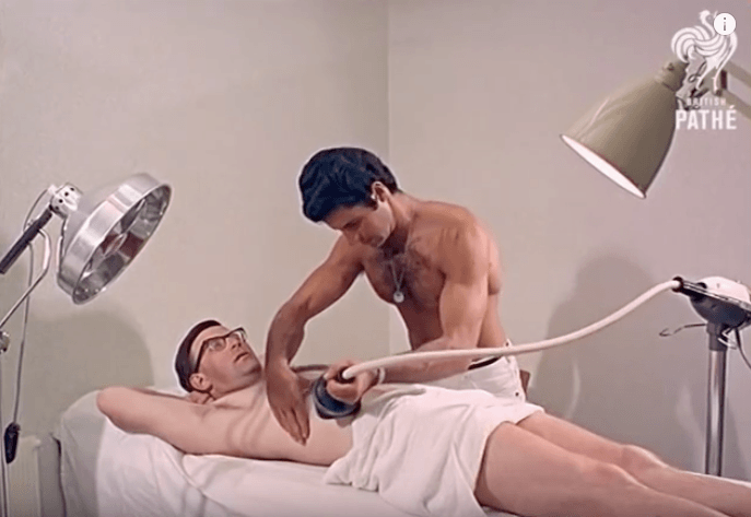 Man using the vibro massage machine for weight loss on his friend Man using the vibro massage machine for weight loss on his friend