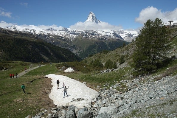 Visitors walk on snow as the Matterhorn stands behind