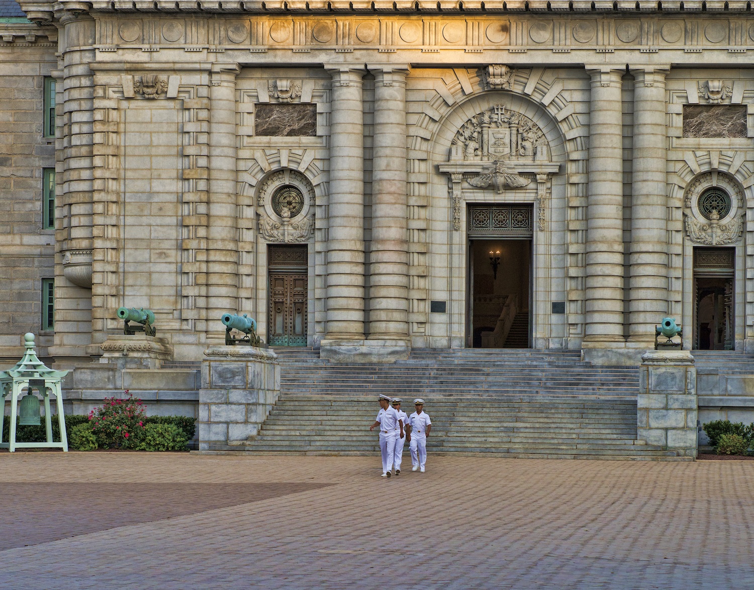 Naval Cadet midshipmen in uniform walk in front of Bancroft Hall at the U.S. Naval Academy