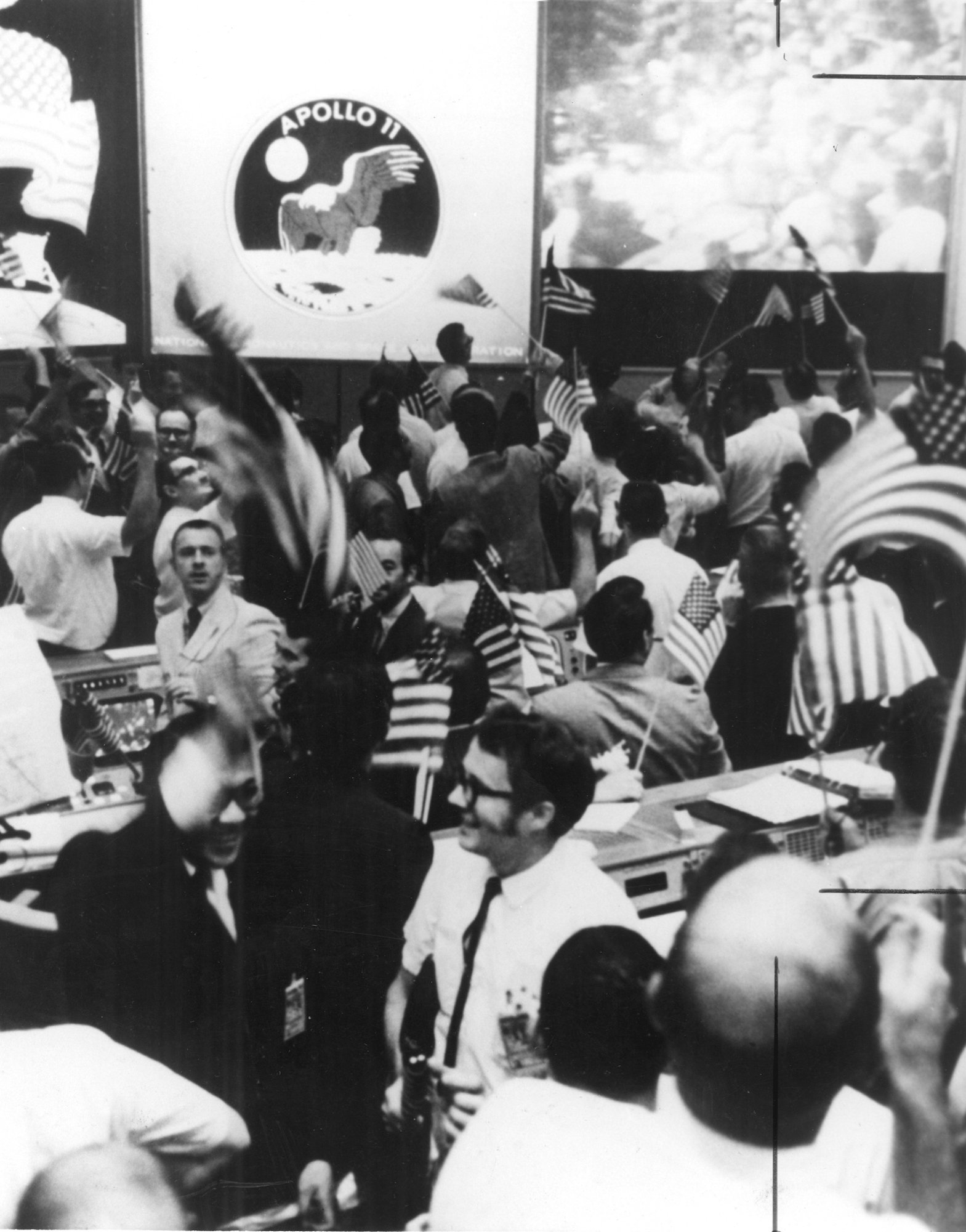 The Mission Operations Control Room in the Mission Control Center at the NASA Manned Spacecraft Center celebrates the success of Apollo 11
