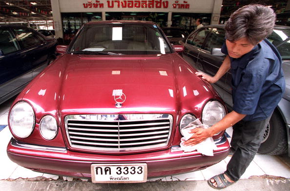 A Thai worker polishes a used Mercedes at a secondhand car market in Bangkok 13 July 1999