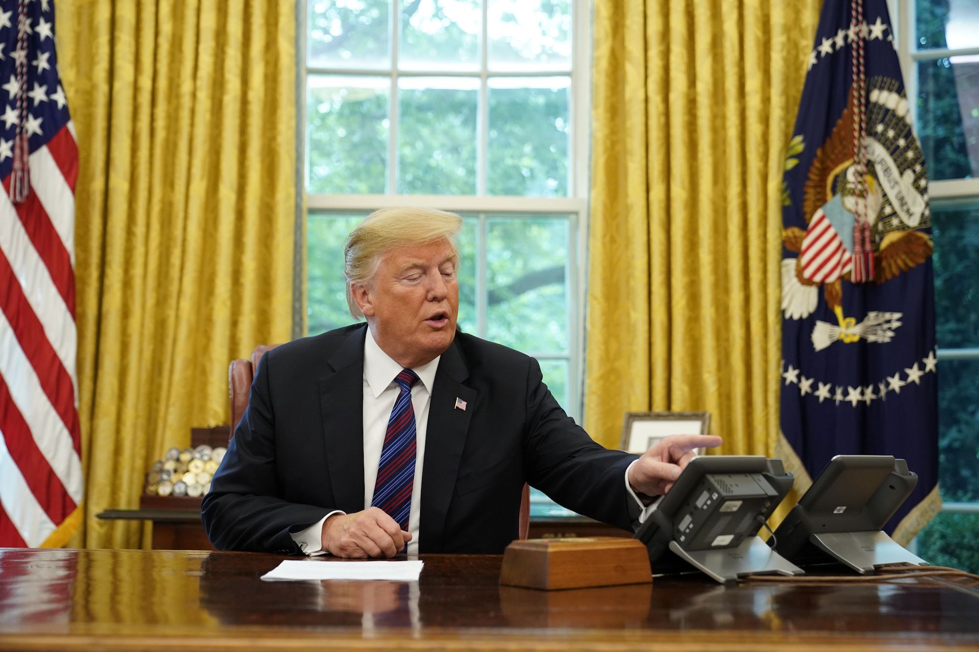 Donald Trump looks at his telephone from the Oval Office