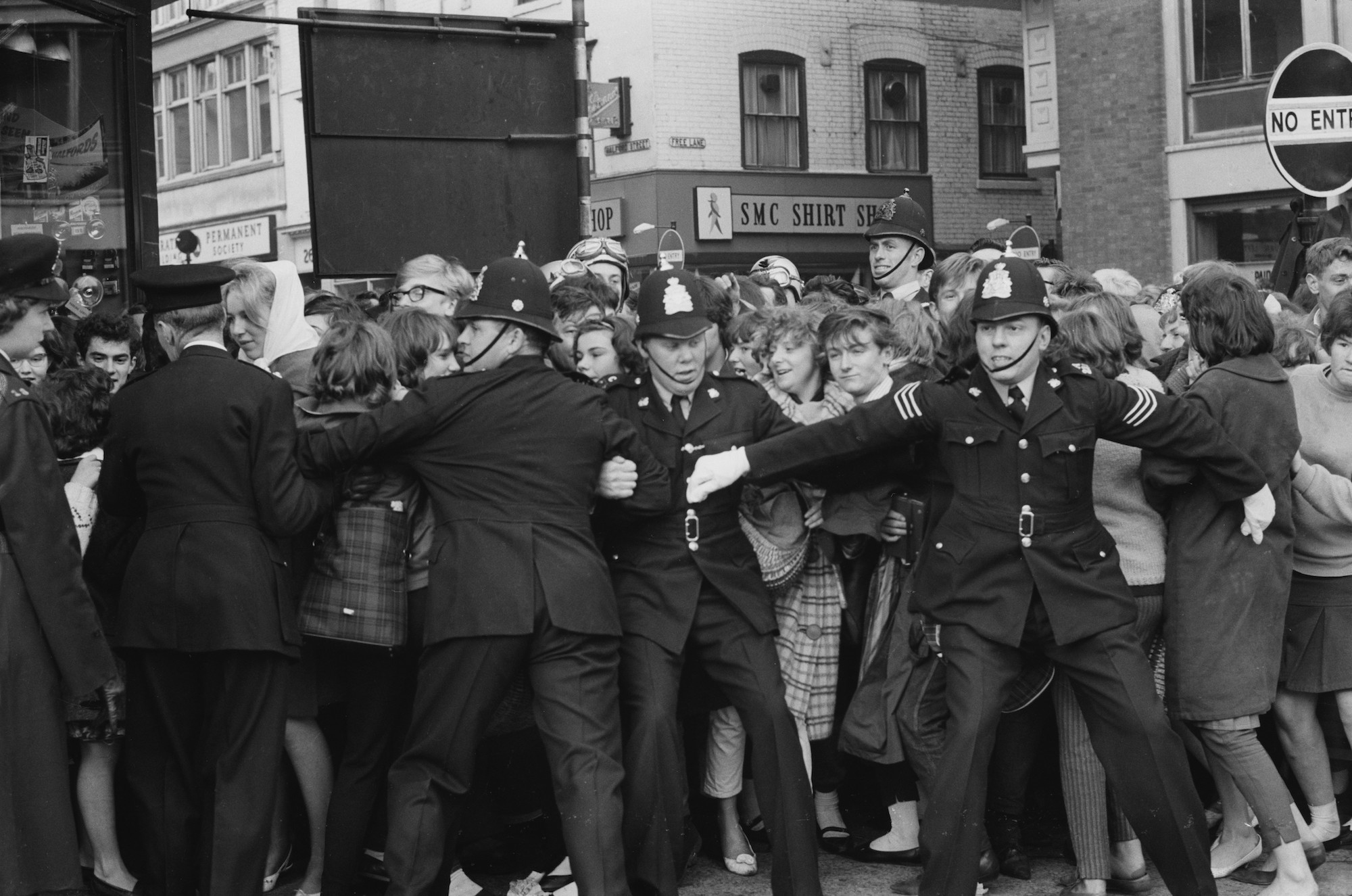 Police holding back crowds of teenagers in a queue for tickets to a Beatles concert