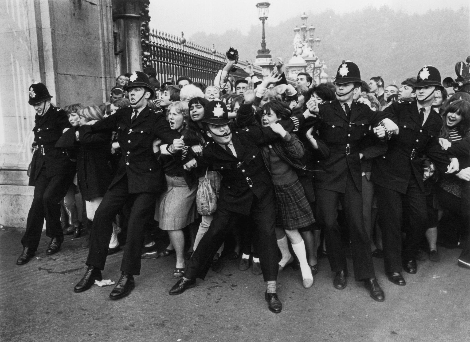 Police keeping back a crowd of young fans outside Buckingham Palace
