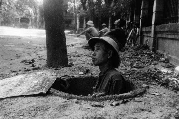 A member of the public seeks refuge in an air-raid shelter in Hanoi, while American bombers raid the city