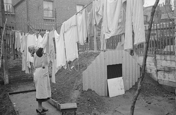 A woman hanging out her washing next to the new Anderson air raid shelter in her back yard