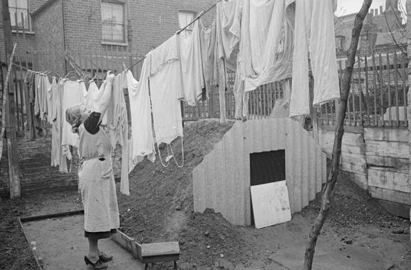 A woman hanging out her washing next to the new Anderson air raid shelter in her back yard A woman hanging out her washing next to the new Anderson air raid shelter in her back yard