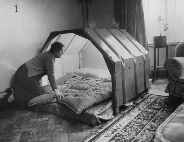 1940: A woman makes the bed in an indoor bomb shelter. 1940: A woman makes the bed in an indoor bomb shelter.