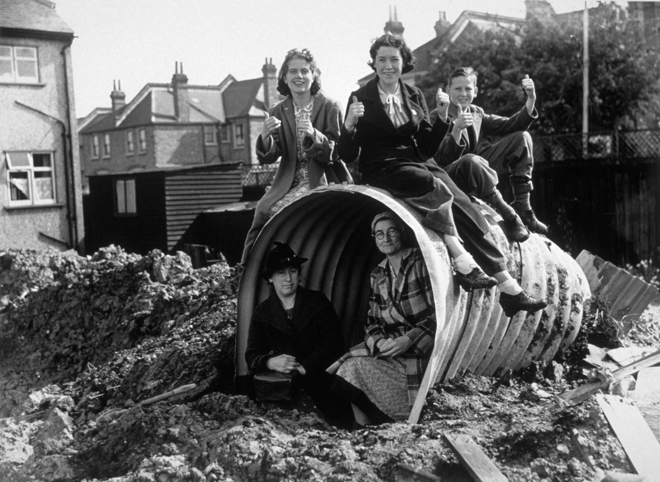 A family sitting on and in their air raid shelter A family sitting on and in their air raid shelter