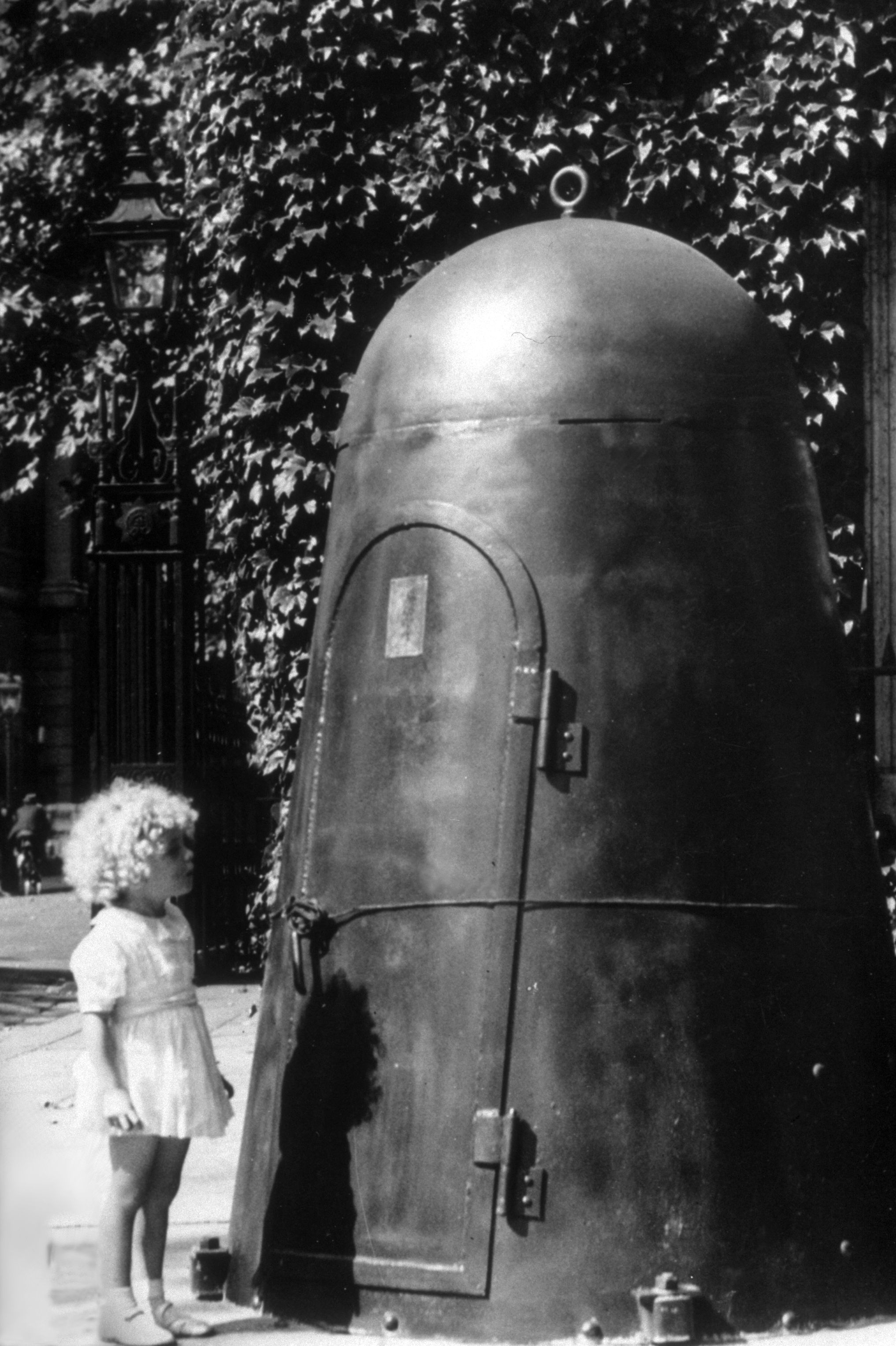 A young girl looking at the entrance to a public air-raid shelter.