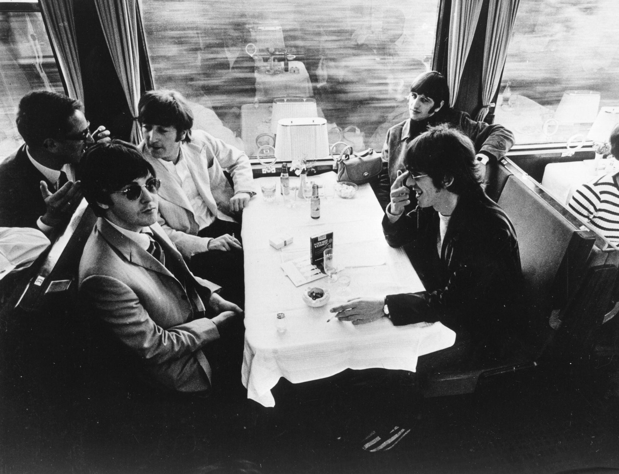 The Beatles relax in the buffet car of a train, during a tour of Europe