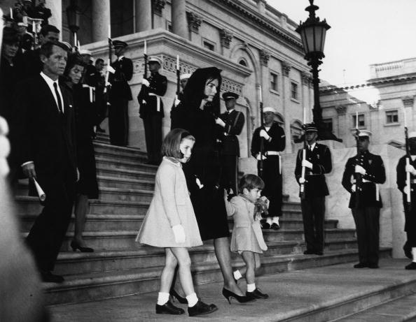 Jackie Kennedy and her children John Jr. and Caroline, walking down steps past a guard of honour at the funeral of President Kennedy. Robert Kennedy is following them