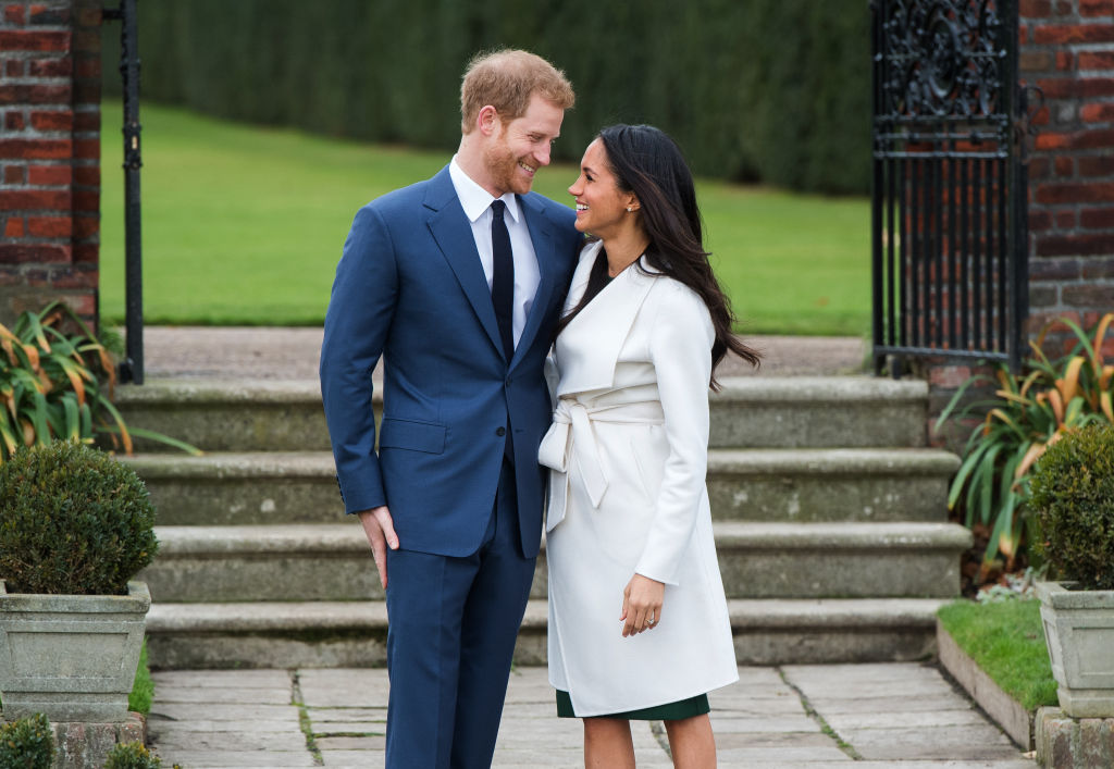 Prince Harry and Meghan Markle smiling at each other outside of Nottingham Cottage.