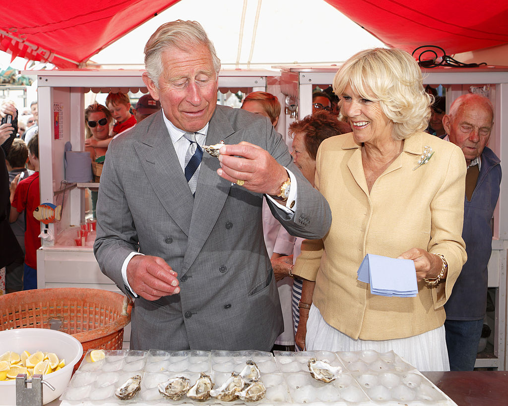 Prince Charles eating oysters with Camilla next to him