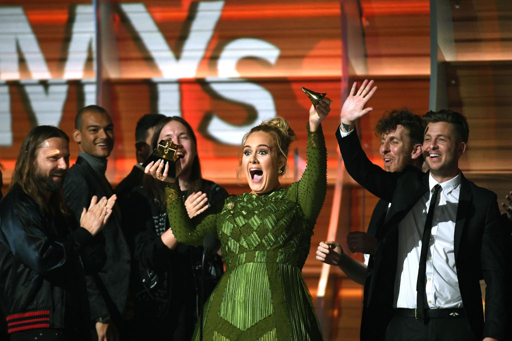 Singer Adele breaks the top off of her award and waves to the audience at the 2017 Grammy Awards