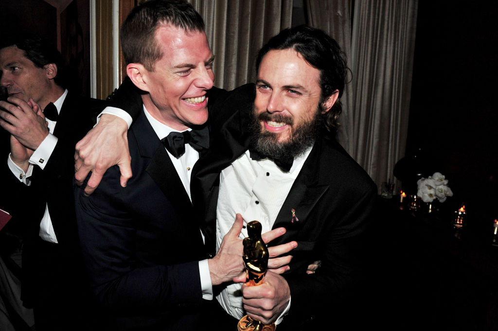 Backstage, Casey Affleck smiles and holds his Oscar award for best actor in 'Manchester By The Sea'