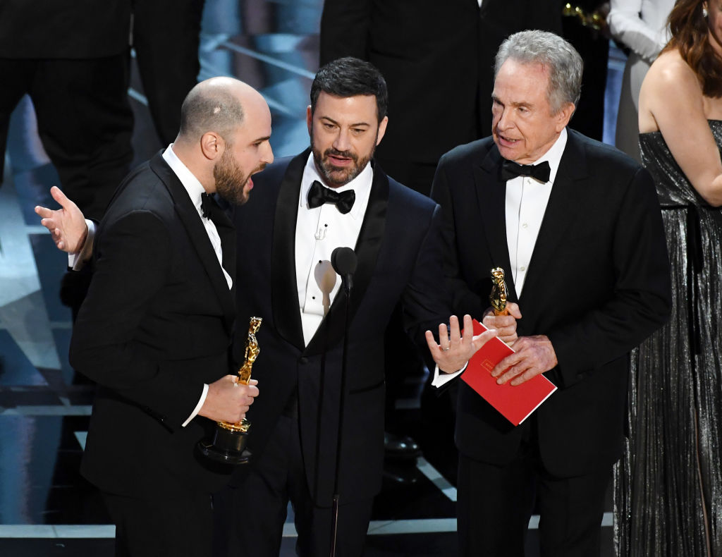 La La Land producer Jordan Horowitz speaks into the microphone as Oscar host Jimmy Kimmel attempts clarify the mixup for Best Picture