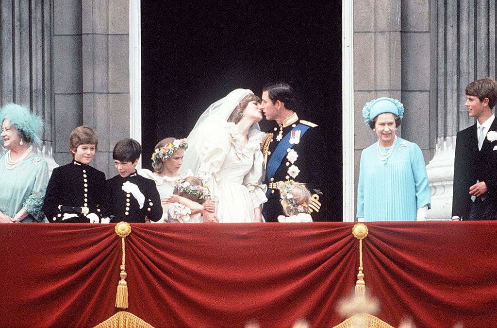 Princess Diana and Prince Charles kissing on balcony of Buckingham Palace after wedding ceremony.