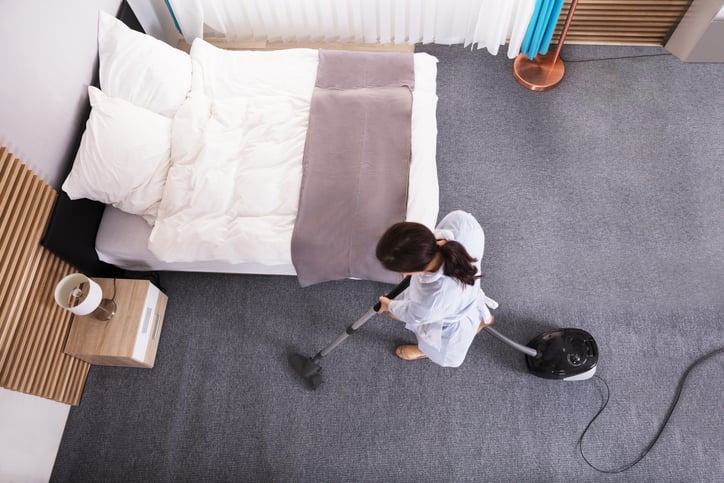 Housekeeper vacuuming a hotel room