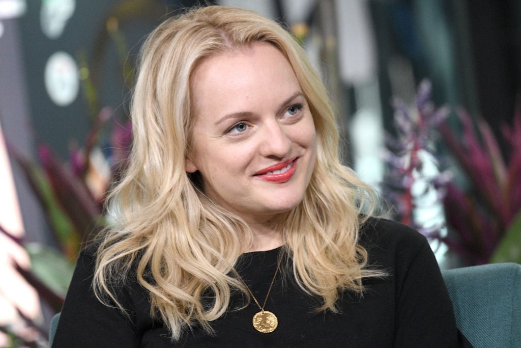 Elisabeth Moss smiling and wearing a black sweater and gold necklace