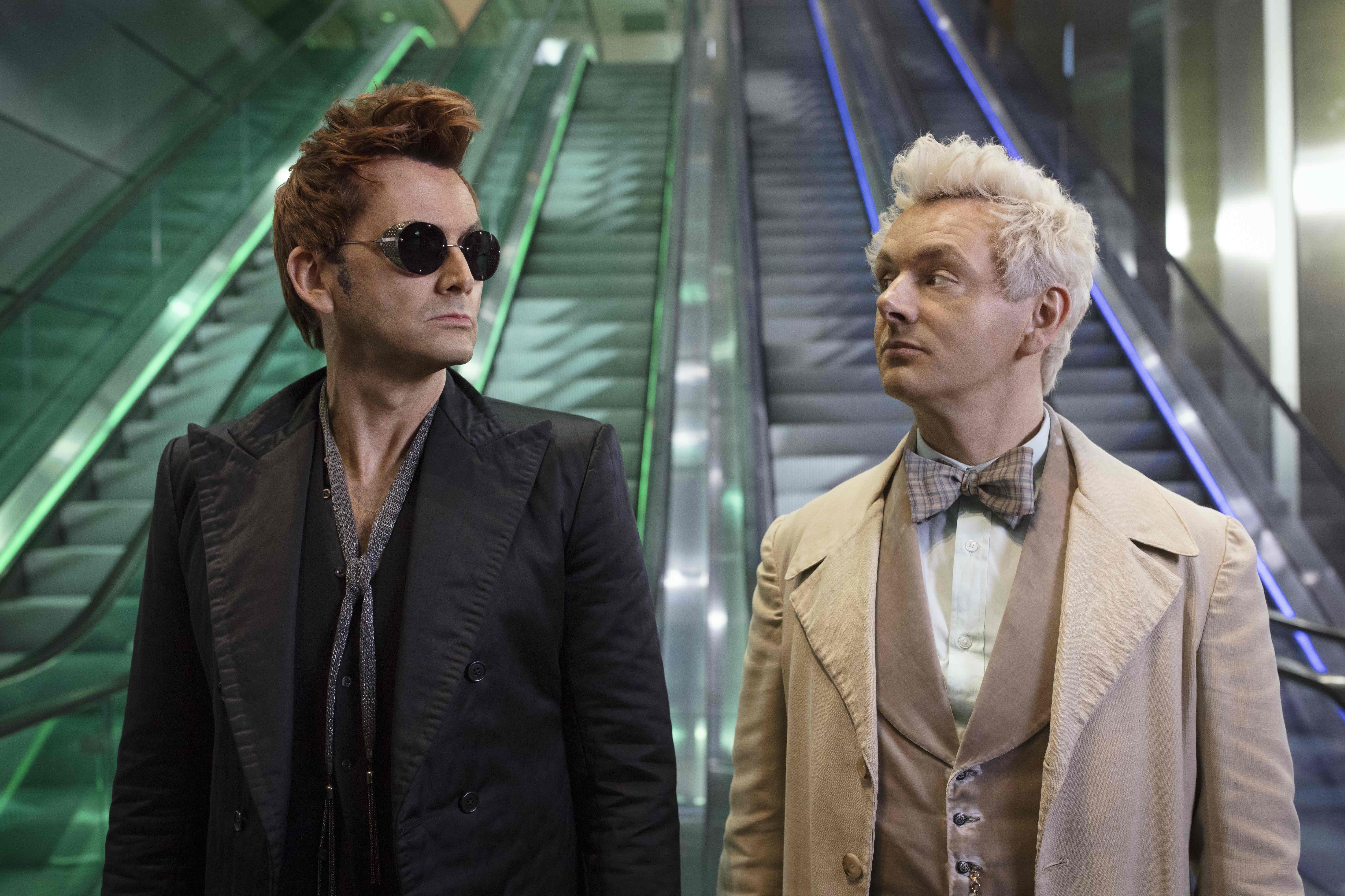 David Tennant, wearing sunglasses and black suit, and Michael Sheen, wearing a white suit, in 'Good Omens' 