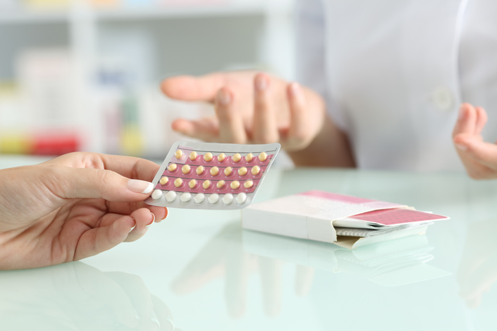 A woman holding birth control pills