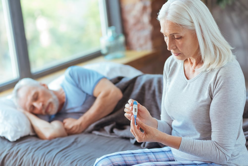 Woman taking a sick man's temperature