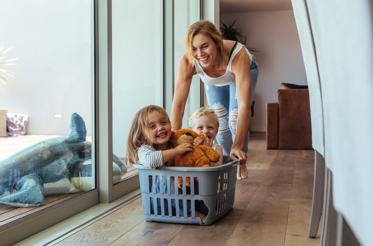Happy woman pushing kids in a laundry basket