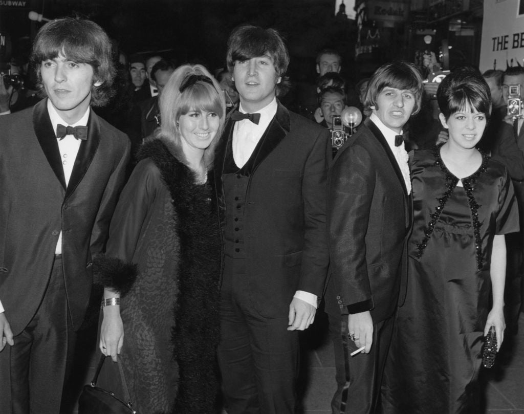 George Harrison, Cynthia Lennon, John Lennon, Ringo Starr, and Maureen Starkey wear formal wear and stand in a line in front of a crowd.