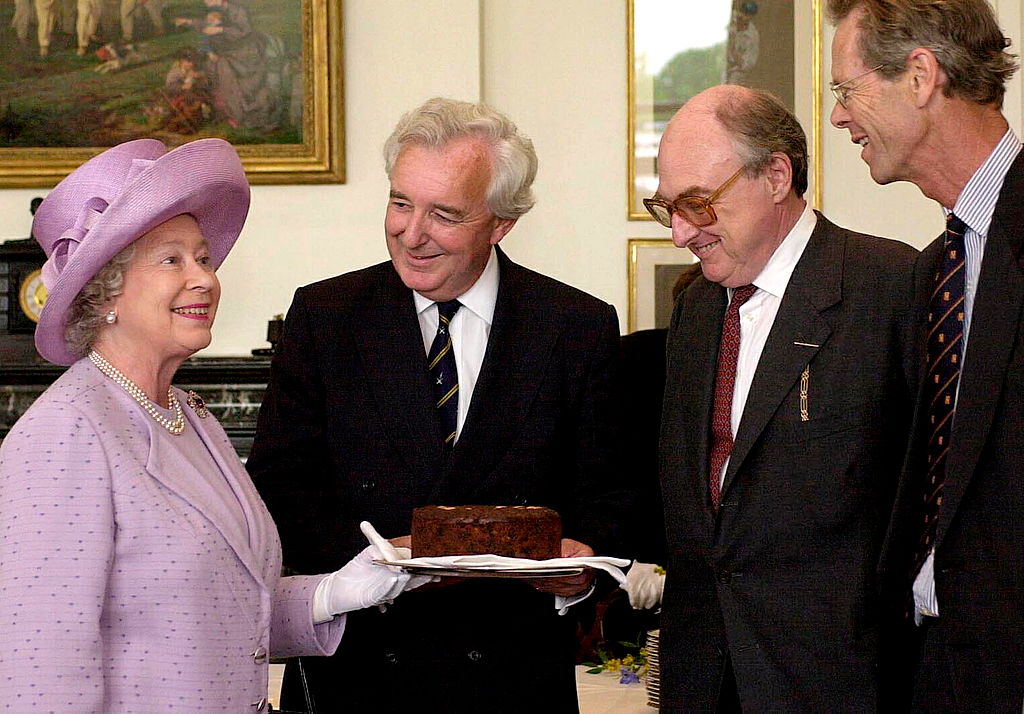 Queen Elizabeth II holding a chocolate cake: